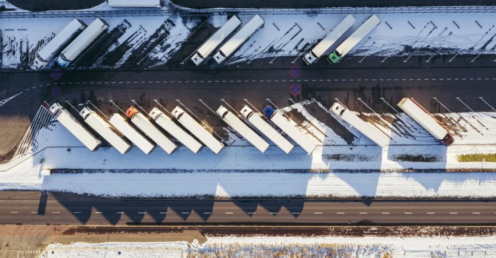 White linehaul trucks in parked in snow.